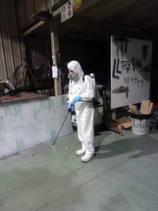 Un hombre con un traje de protección está rociando una pared con un pulverizador.