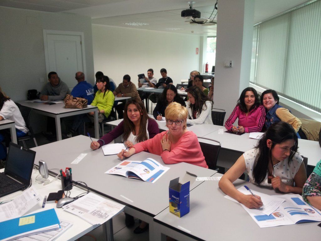 Un grupo de personas están sentadas en mesas en un aula.
