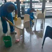 Dos hombres están limpiando sillas en una habitación.