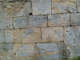 Un primer plano de un muro de piedra hecho de ladrillos cuadrados.