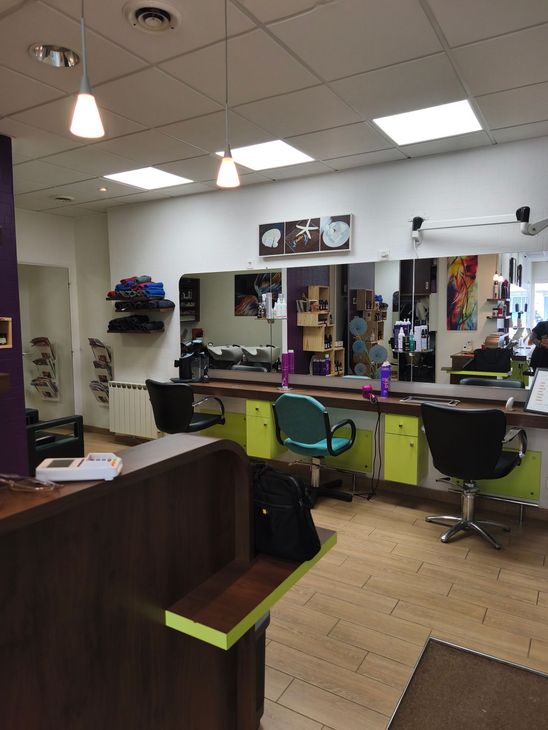 Intérieur du salon avec fauteuils de coiffure, miroirs, lavabos et décor noir et vert