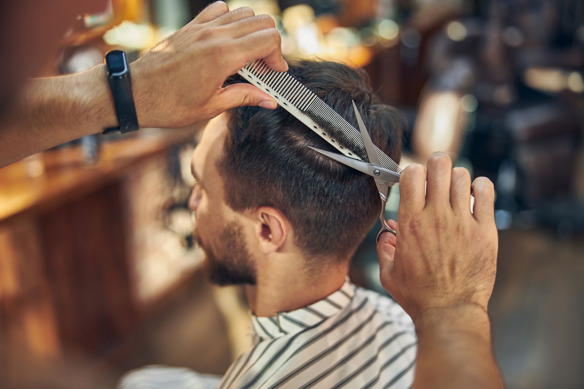 Un coiffeur coupe les cheveux d'un homme avec un peigne et des ciseaux dans un salon de coiffure