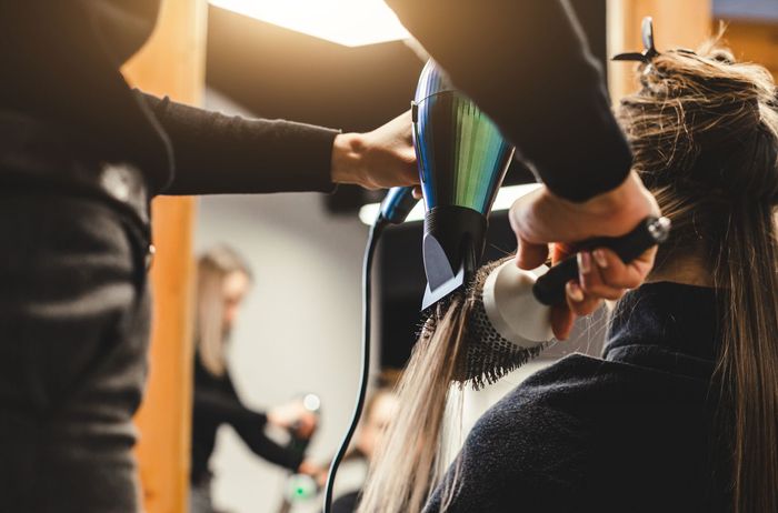 Coiffeuse séchant les cheveux d'une cliente dans un salon