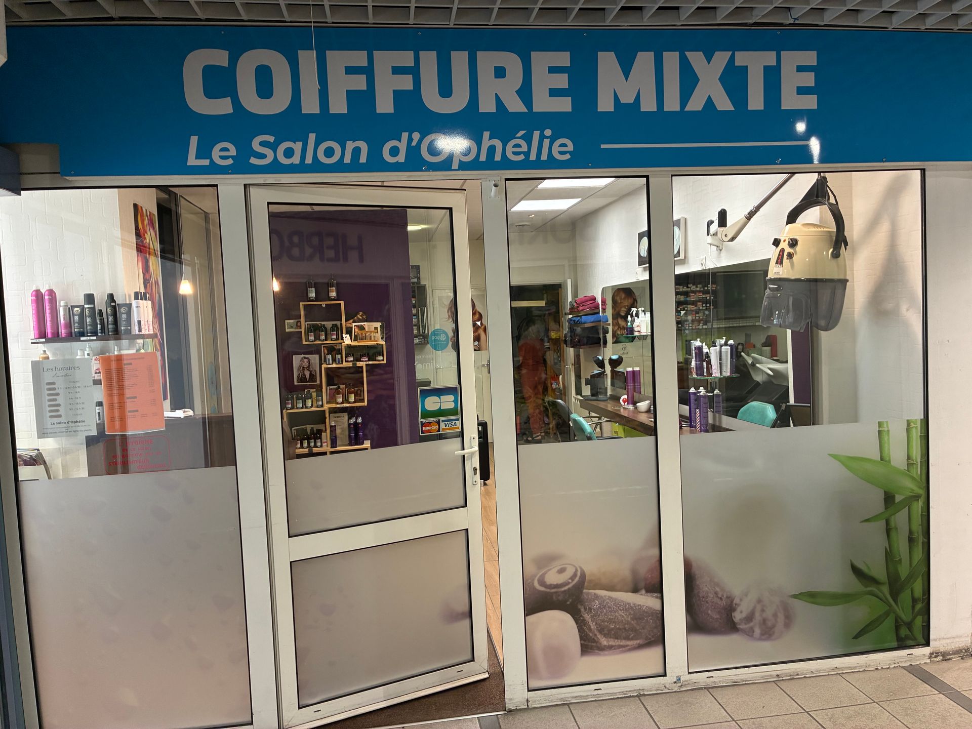 Façade du salon de beauté Coiffure Mixte, avec une enseigne bleue et une entrée vitrée