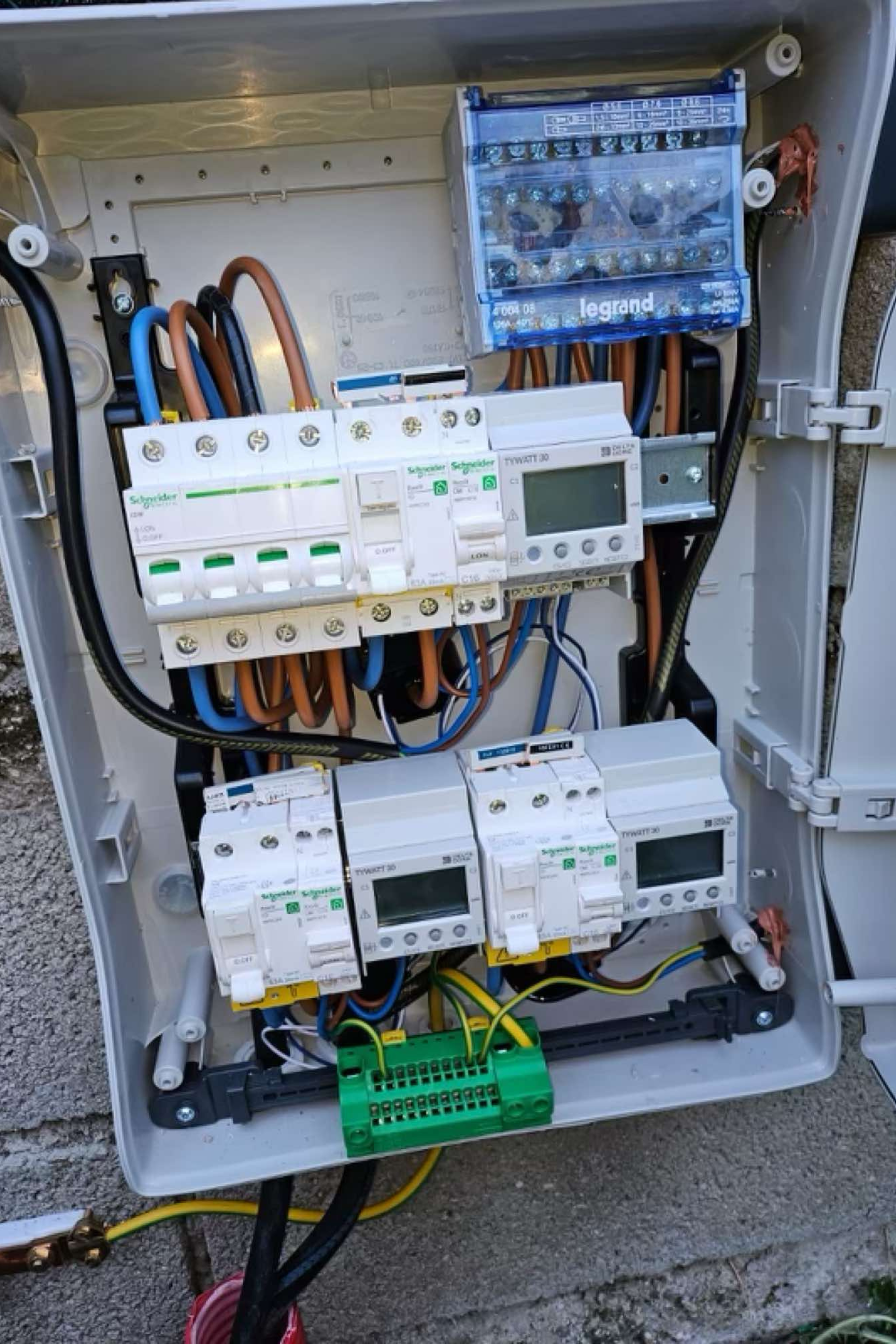 Une personne portant des gants travaille sur un boîtier électrique.