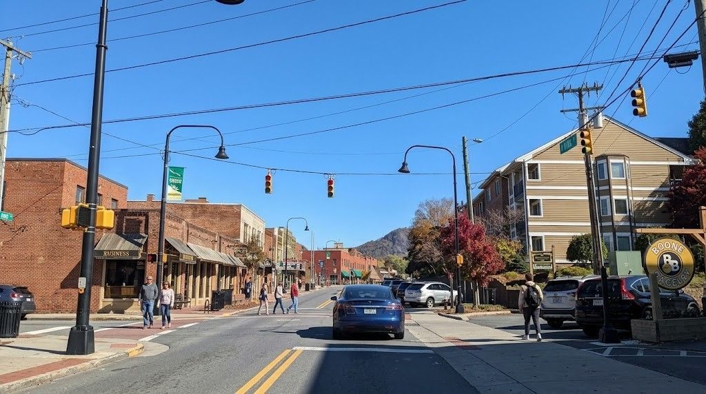 Downtown street with cars, storefronts, traffic lights, and blue sky on a sunny day