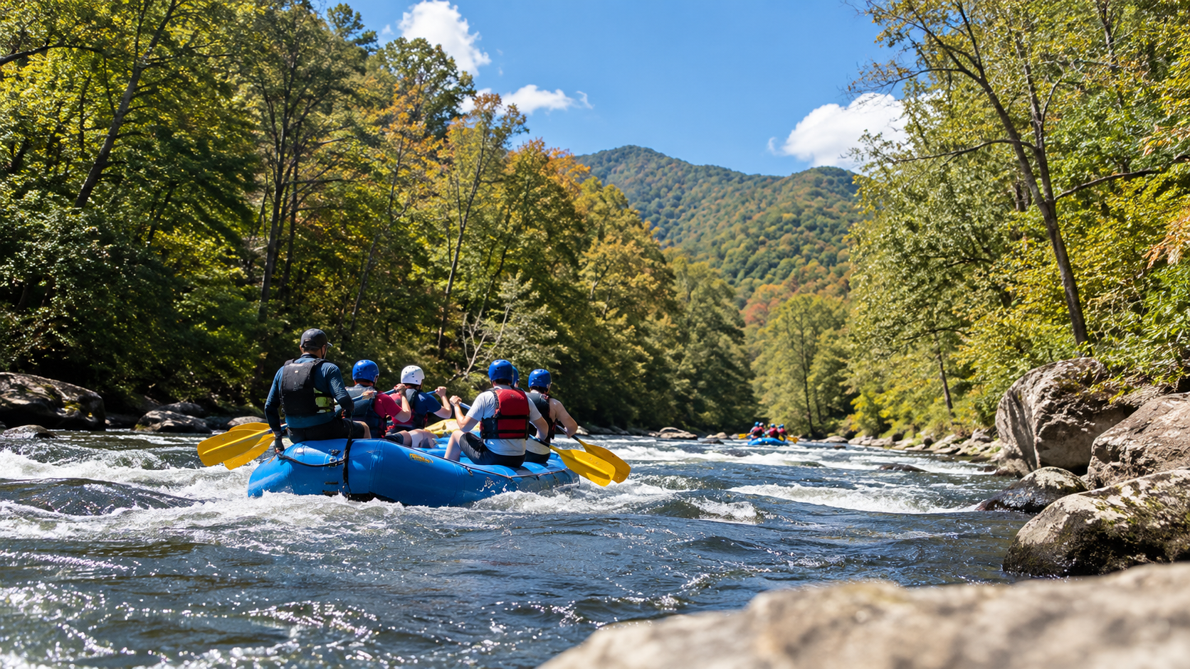 Group whitewater rafting in blue rafts on a river surrounded by forested mountains