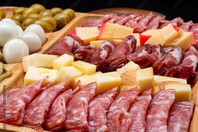 Planche de charcuterie avec salami, cubes de fromage, œufs durs et olives.