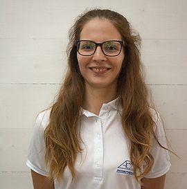 Une femme portant des lunettes et une chemise blanche sourit à la caméra.