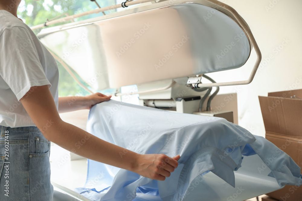 BUDAK'S Textilreinigung GmbH - Frau bügelt Hemd mit Industriebügeleisen