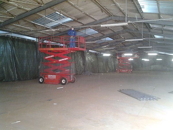Eine rote Scherenhebebühne steht in einer leeren Lagerhalle.