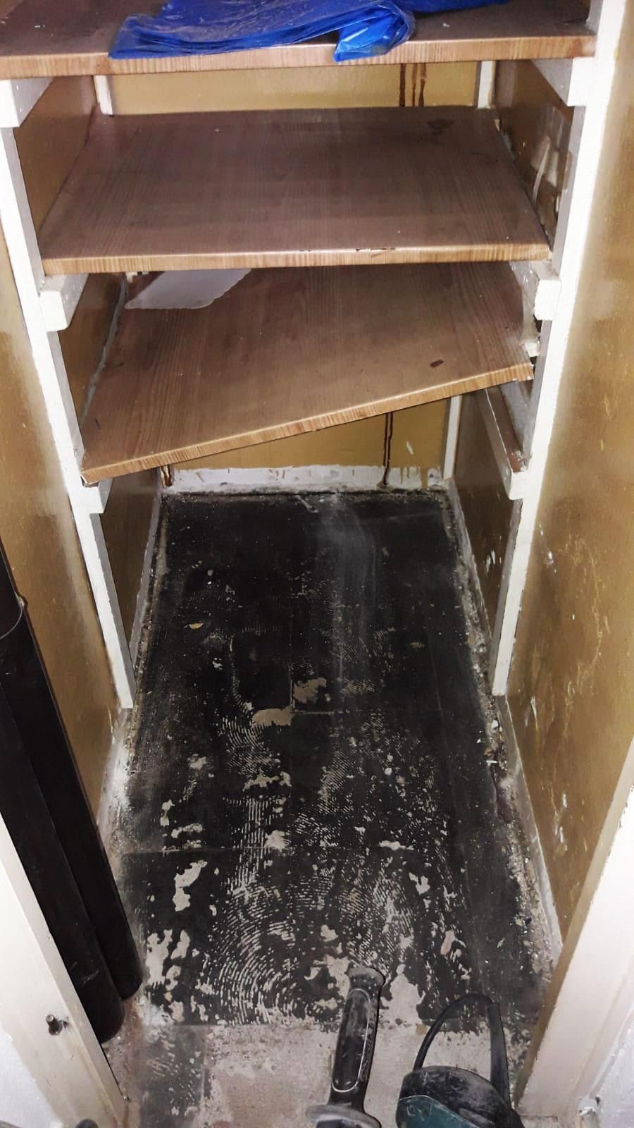 Ein Schrank mit leeren Regalen und schwarzem Boden.