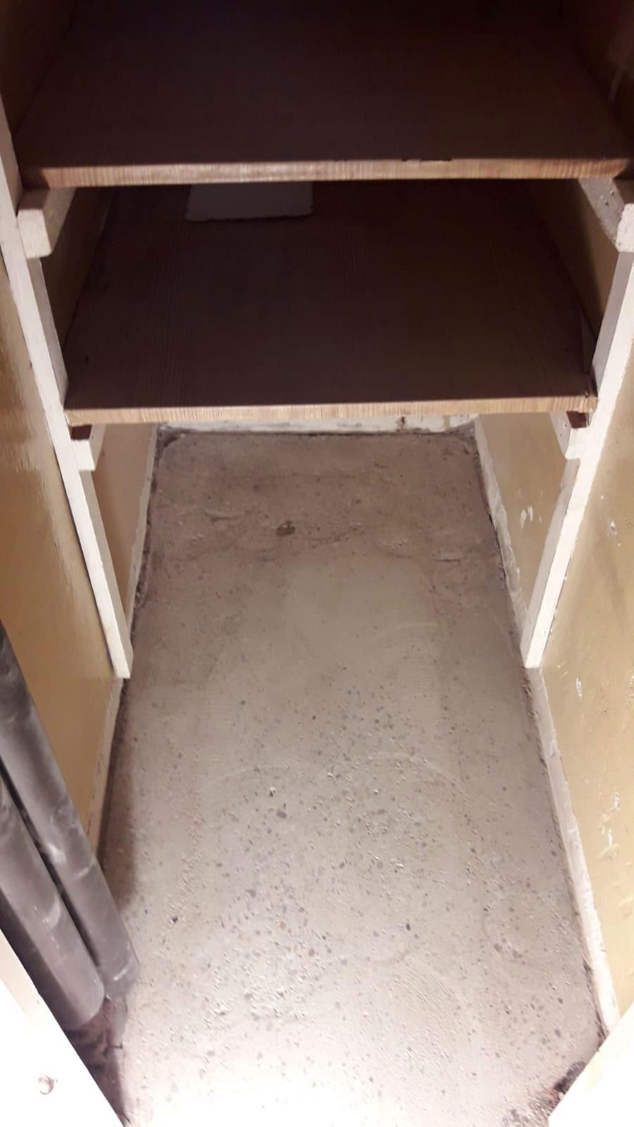 Ein kleiner Schrank mit zwei Regalen und Betonboden.