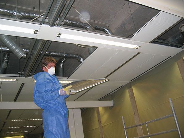 Ein Mann mit einer Maske arbeitet an einer Decke
