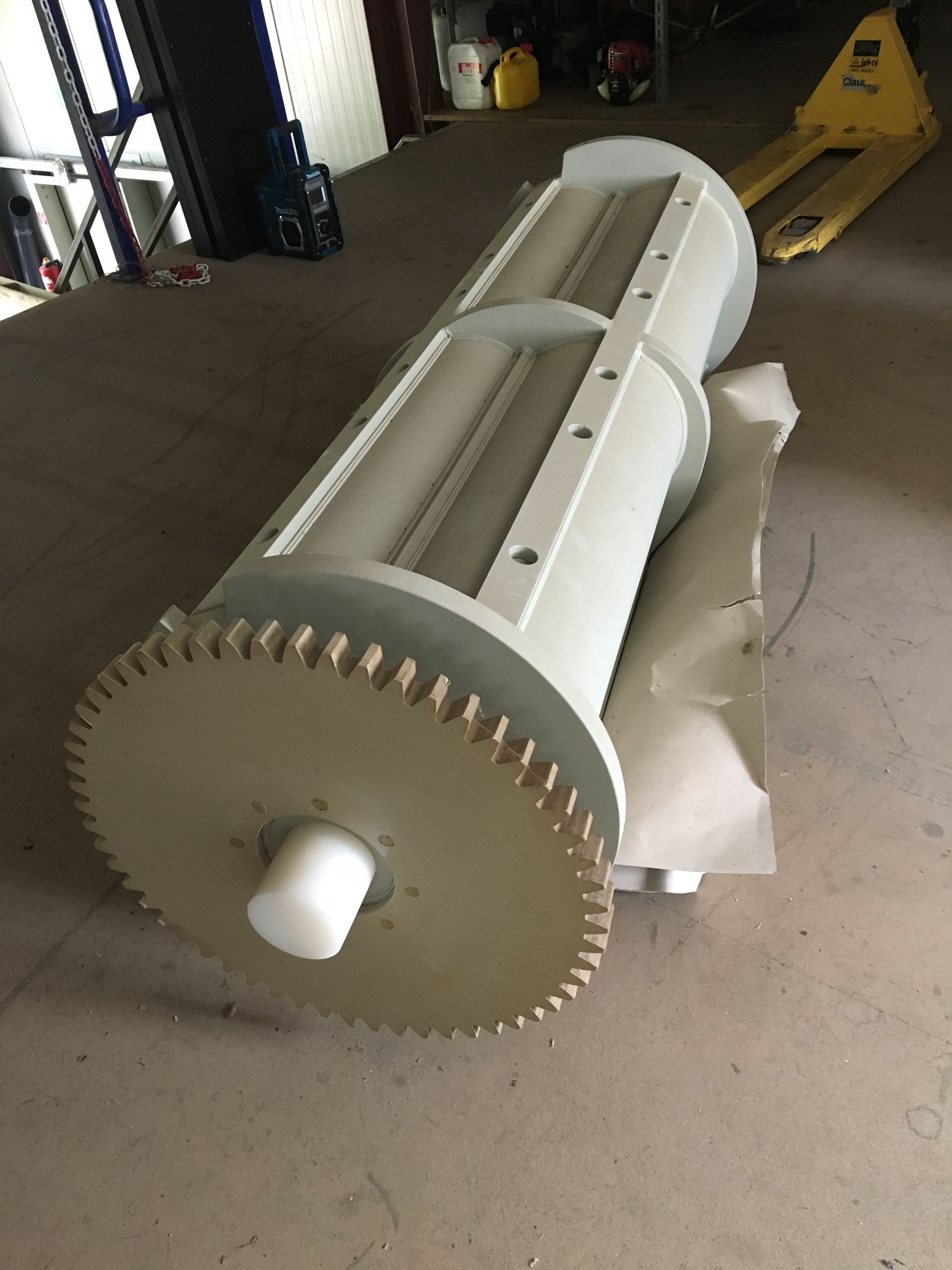 Ein großes weißes Objekt liegt auf dem Boden neben einem gelben Palettenwagen