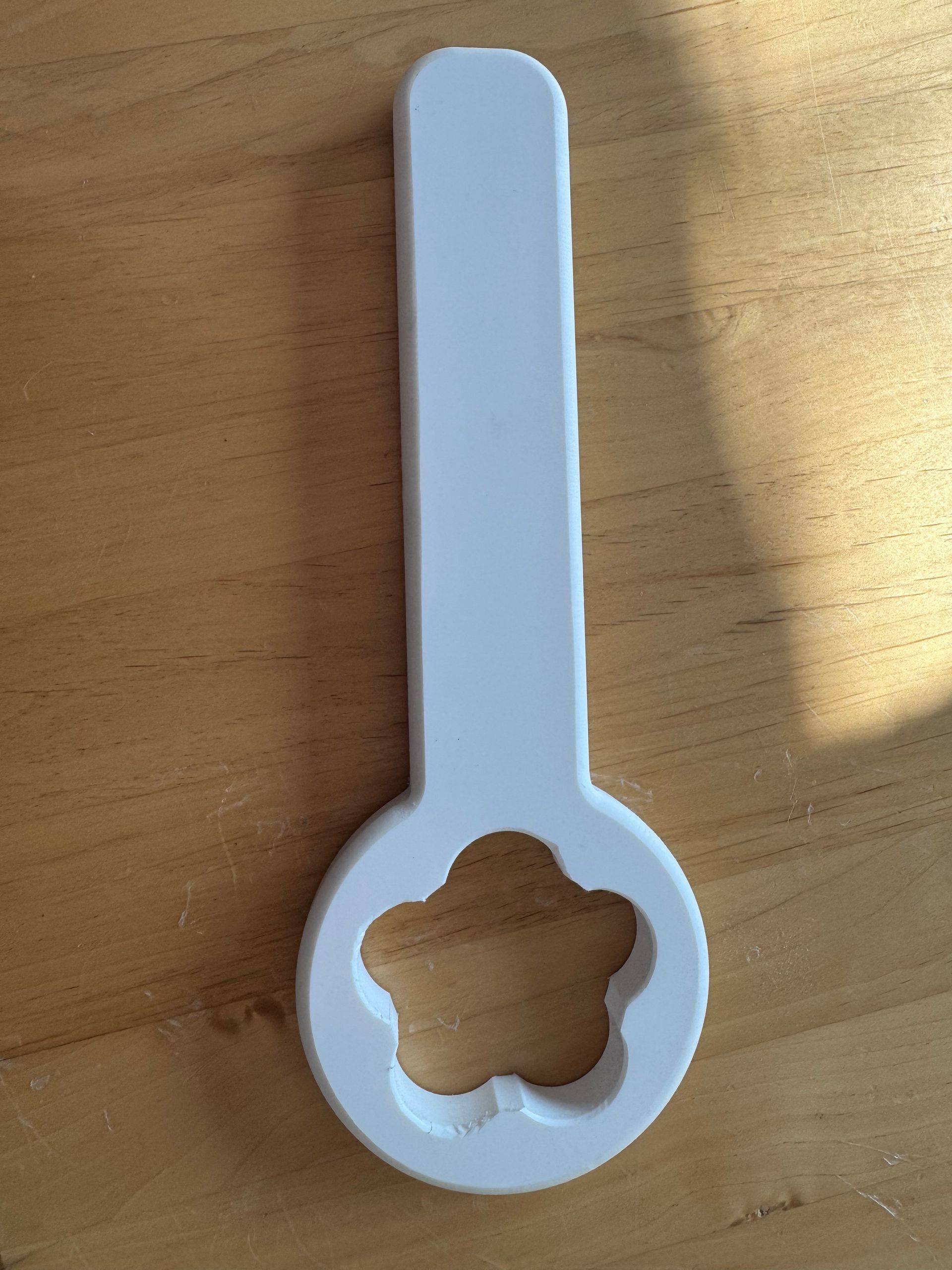 Ein weißer Löffel mit einer Blume in der Mitte ausgeschnitten ist auf einem Holztisch