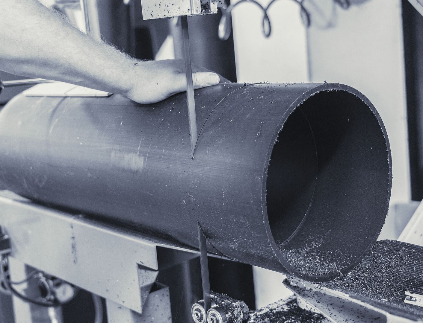 Eine Person schneidet ein Rohr mit einer Bandsäge