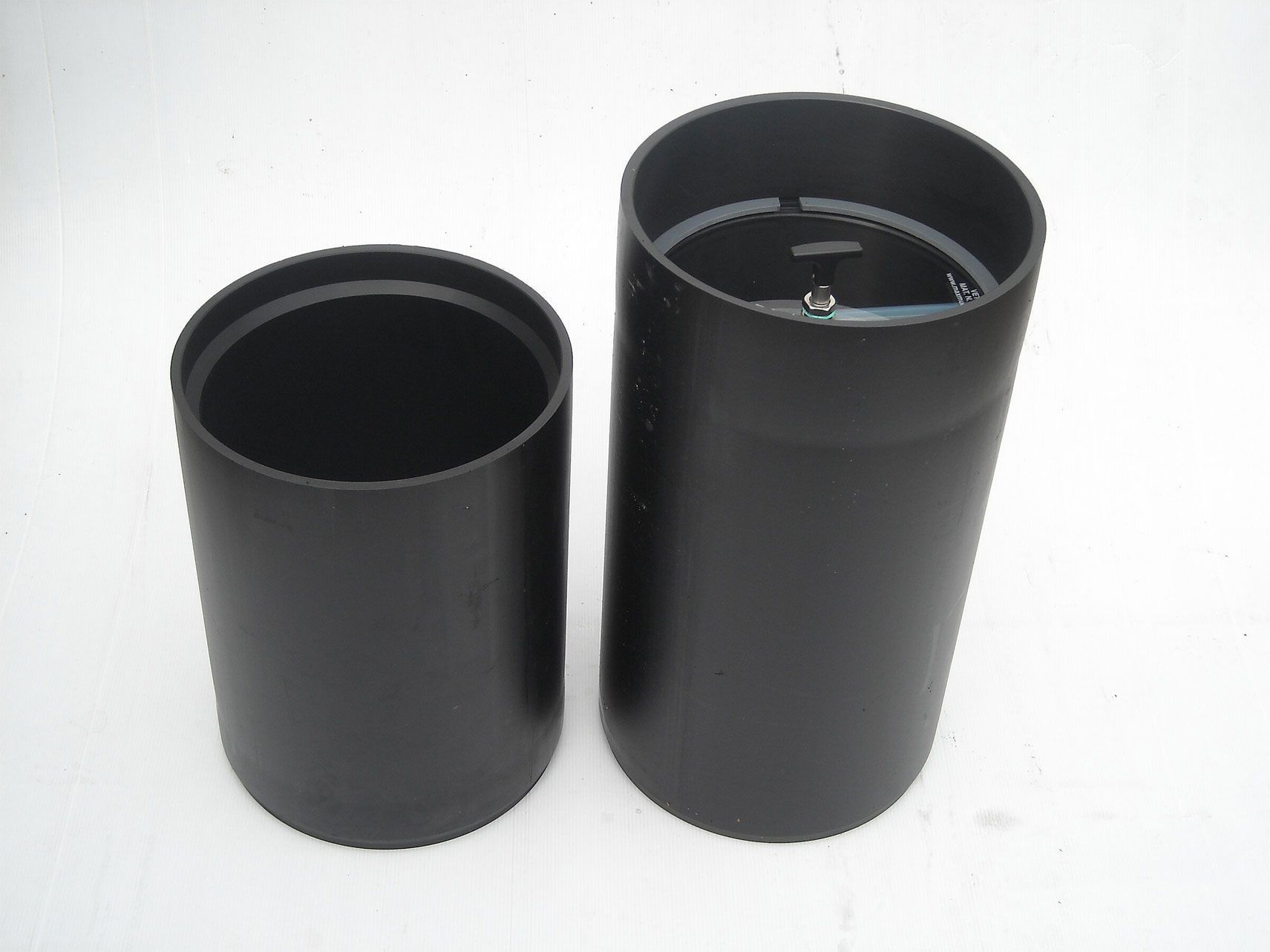 Zwei schwarze Zylinder stehen nebeneinander auf einer weißen Fläche