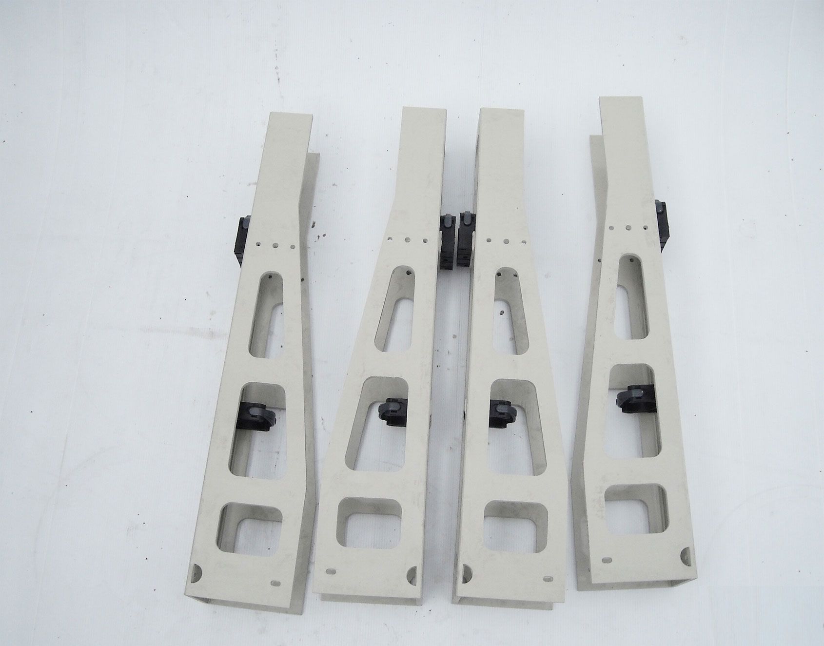 Vier Stücke aus weißem Kunststoff mit schwarzen Schrauben sind auf einer weißen Oberfläche aufgereiht