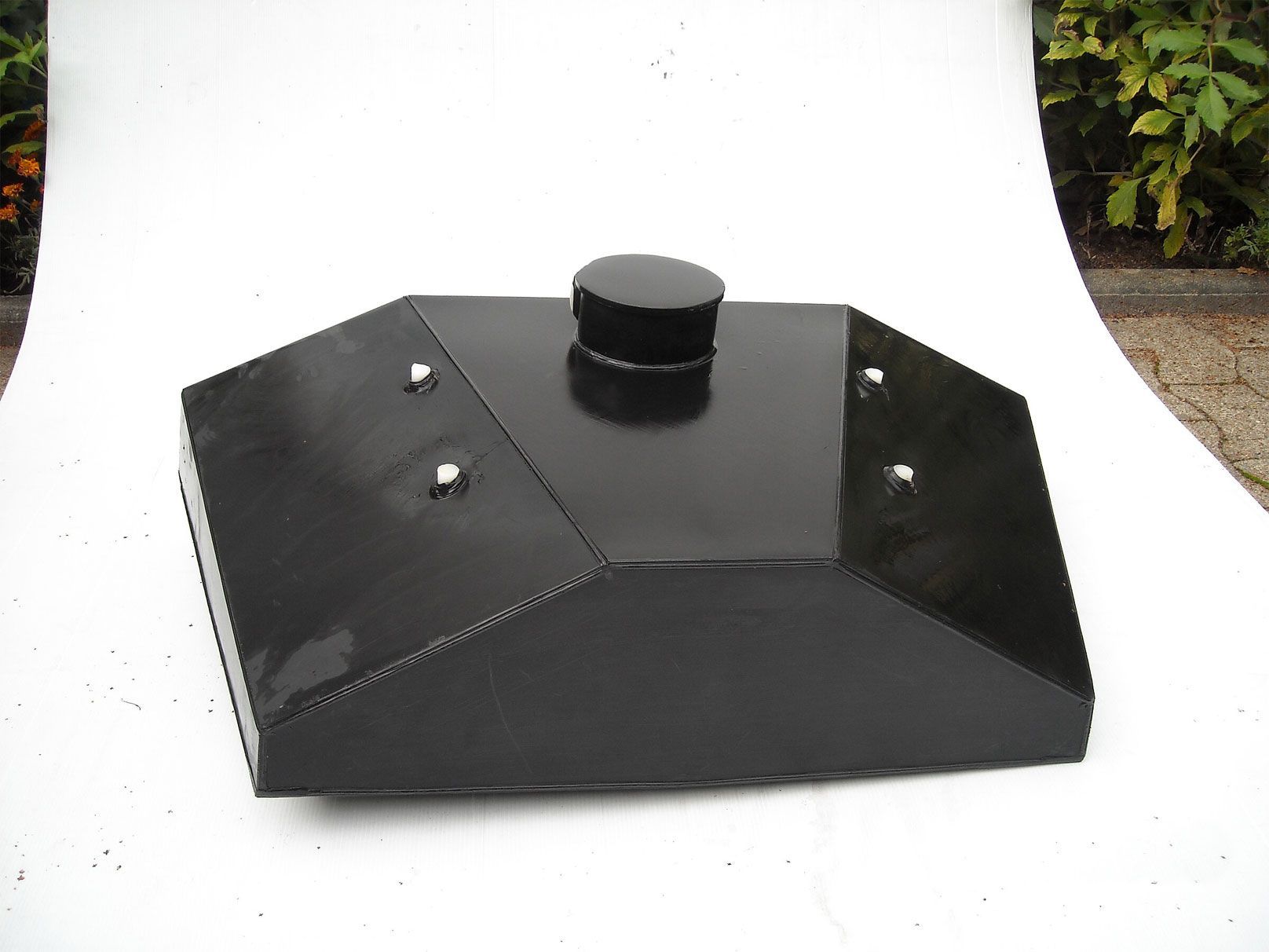 Eine schwarze Box mit Deckel steht auf einer weißen Fläche