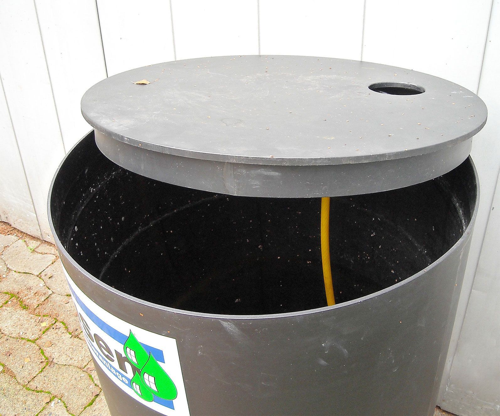 Ein schwarzer Mülleimer mit offenem Deckel und einer gelben Schnur, die herauskommt