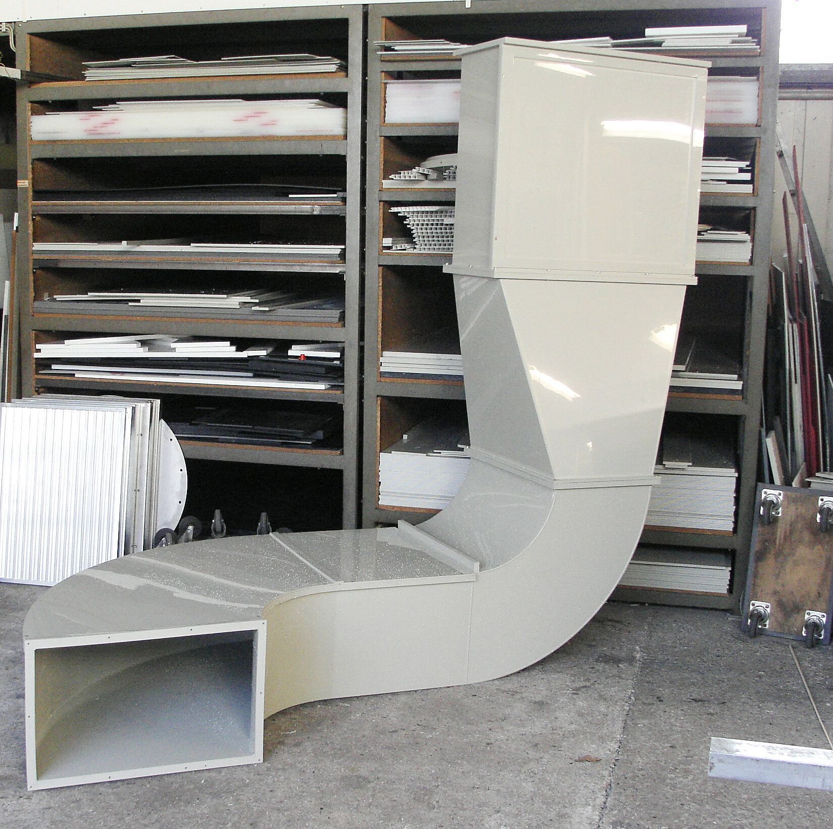 Ein großes weißes Rohr liegt auf dem Boden vor Regalen