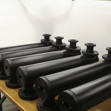 Eine Reihe schwarzer Rohre auf einem Holztisch.