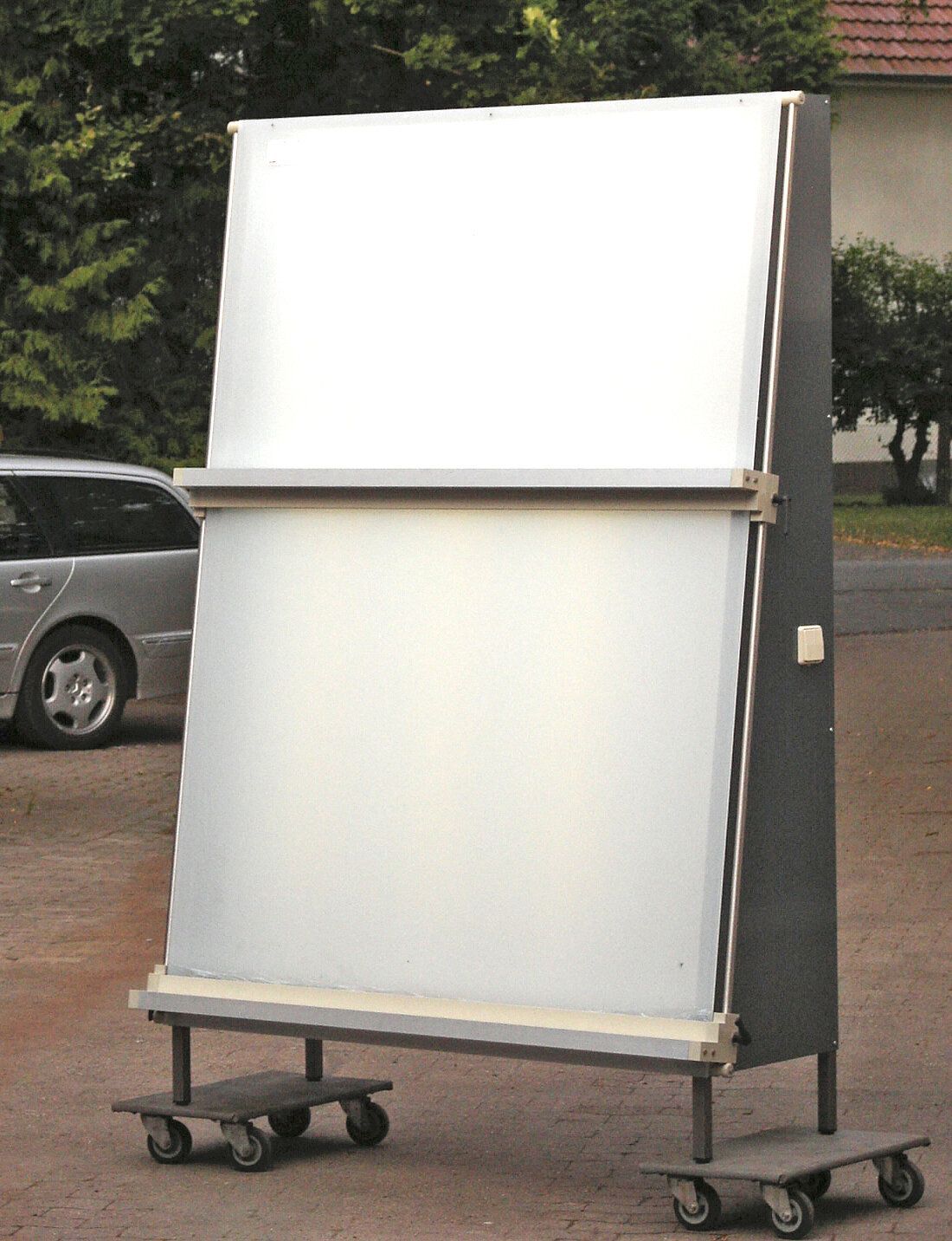 Eine große weiße Tafel liegt auf einem Wagen neben einem Auto