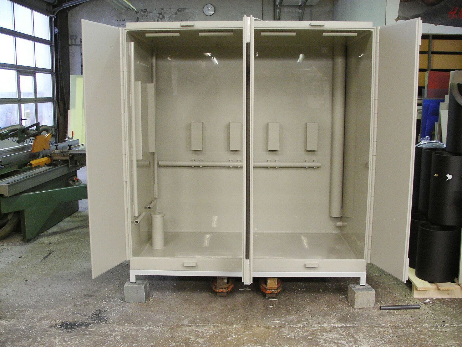 In einem Zimmer steht ein weißer Schrank mit offenen Türen auf dem Boden.