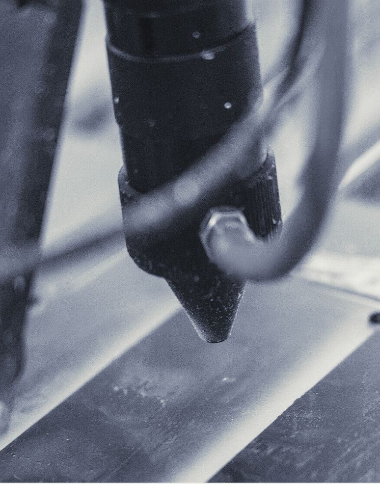 Ein Schwarzweißfoto einer Maschine, die ein Stück Metall schneidet.