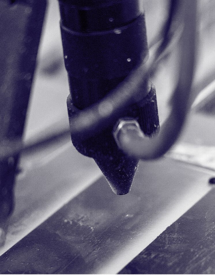Ein Schwarzweißfoto einer Maschine, die ein Stück Metall schneidet.