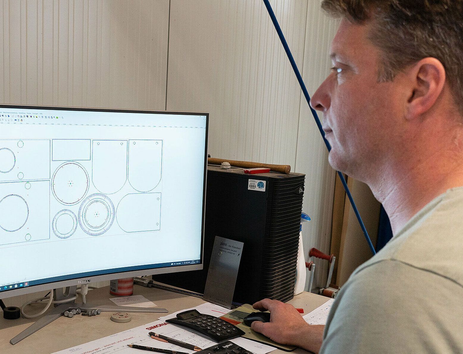 Ein Mann sitzt an einem Schreibtisch und schaut auf einen Computerbildschirm.