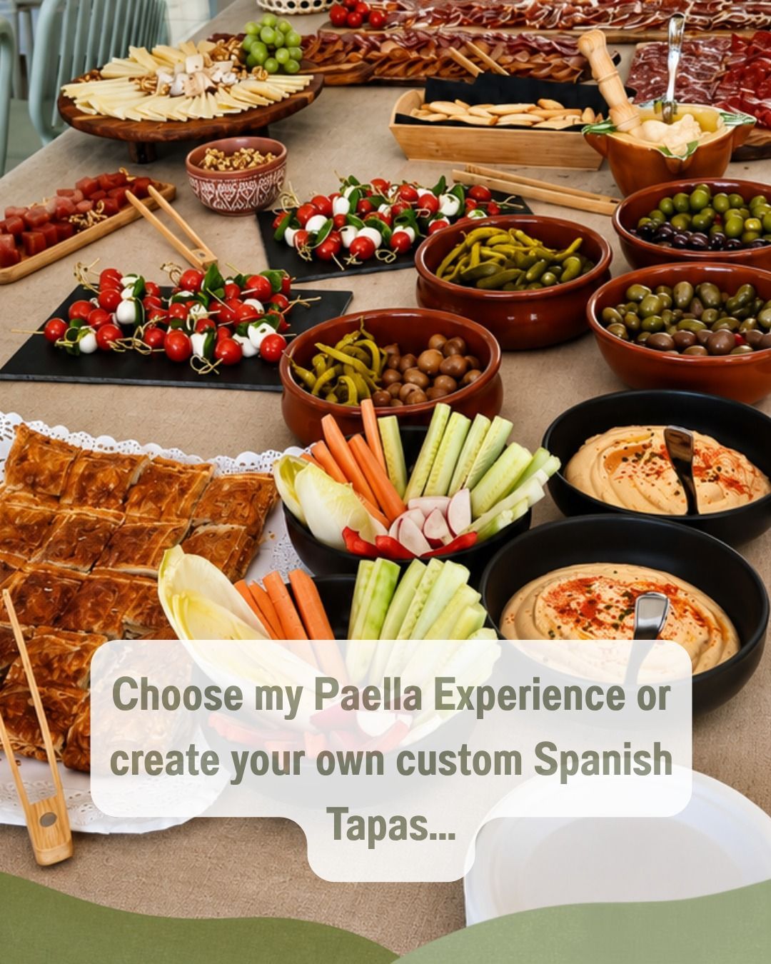 Buffet de tapas españolas con paella, brochetas, aceitunas, verduras y salsas para untar sobre una mesa; texto superpuesto sobre elegir entre paella o tapas