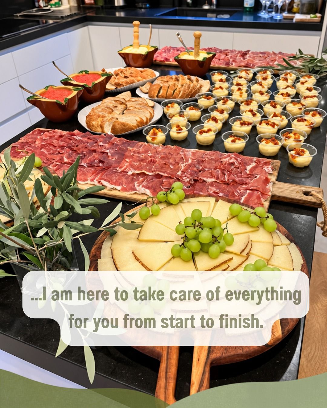 Mesa de charcutería con embutidos, pan, bollería, uvas y aceitunas para un bufé de catering