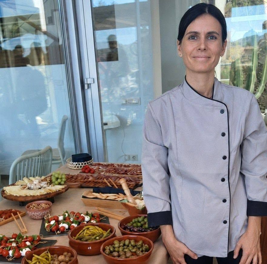 Chef de pie junto a una mesa con una variedad de aperitivos y cuencos pequeños en un patio