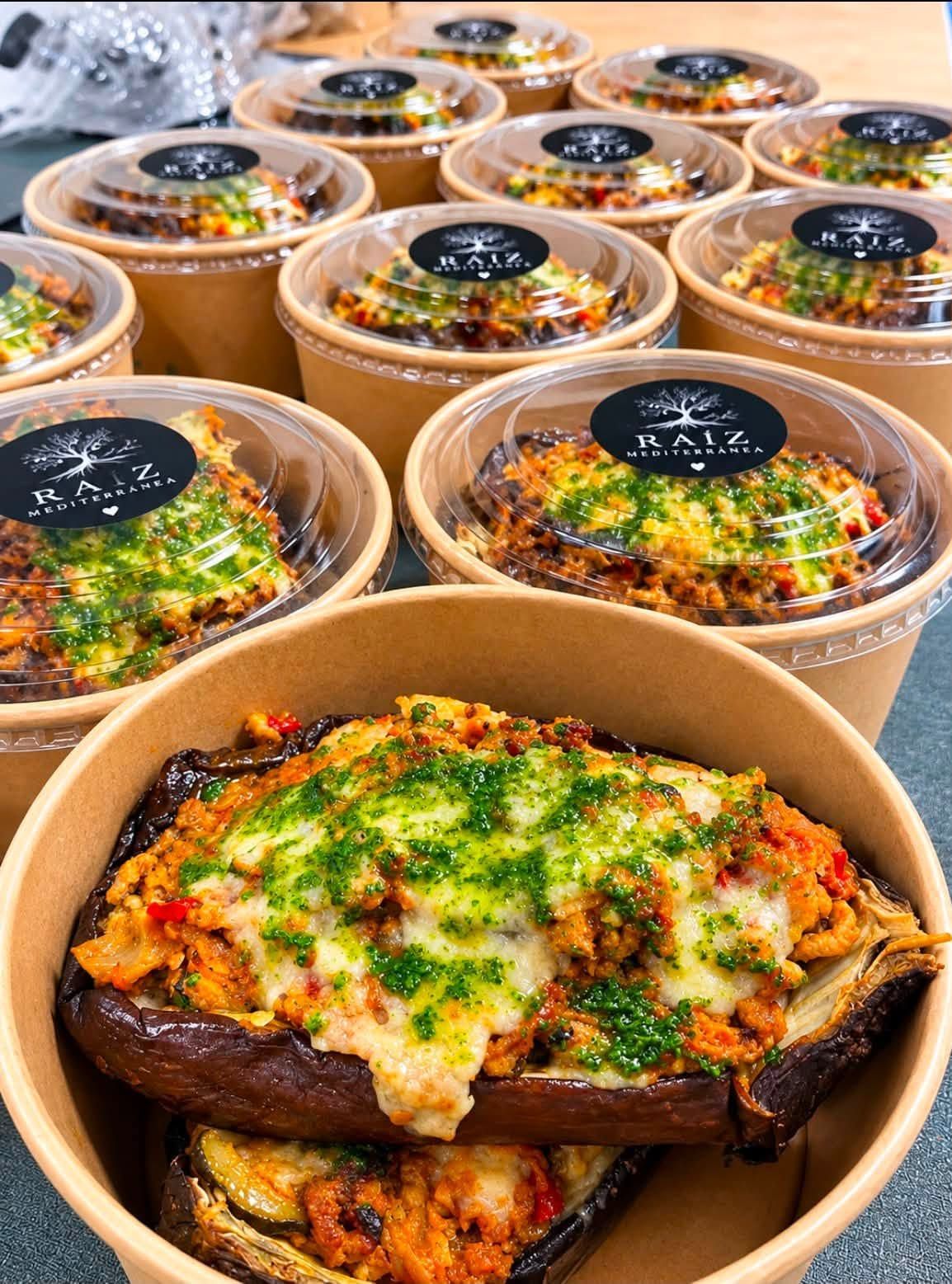 Guisos horneados en moldes de papel, cubiertos con queso fundido y hierbas, dispuestos en filas.