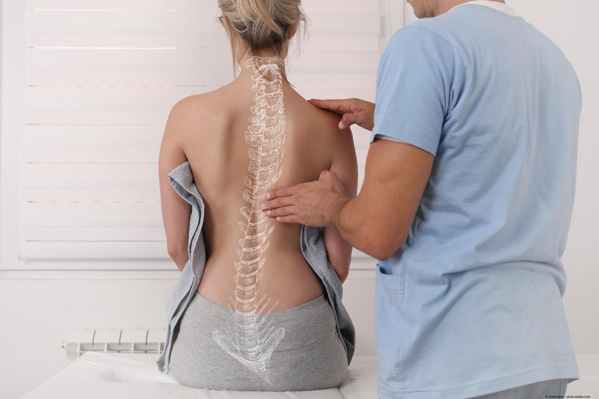 Ein Arzt überprüft die Wirbelsäule einer Patientin am Rücken