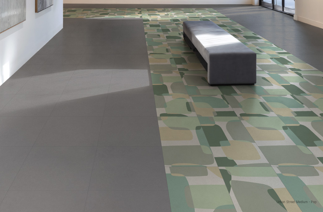 Habitación vacía con azulejos, grandes ventanales y una columna blanca que refleja la luz en el suelo.