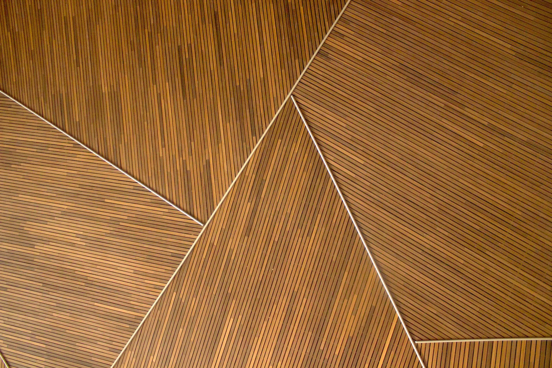 Habitación minimalista con bancos de madera y ventanas inclinadas que dejan entrar la luz natural.
