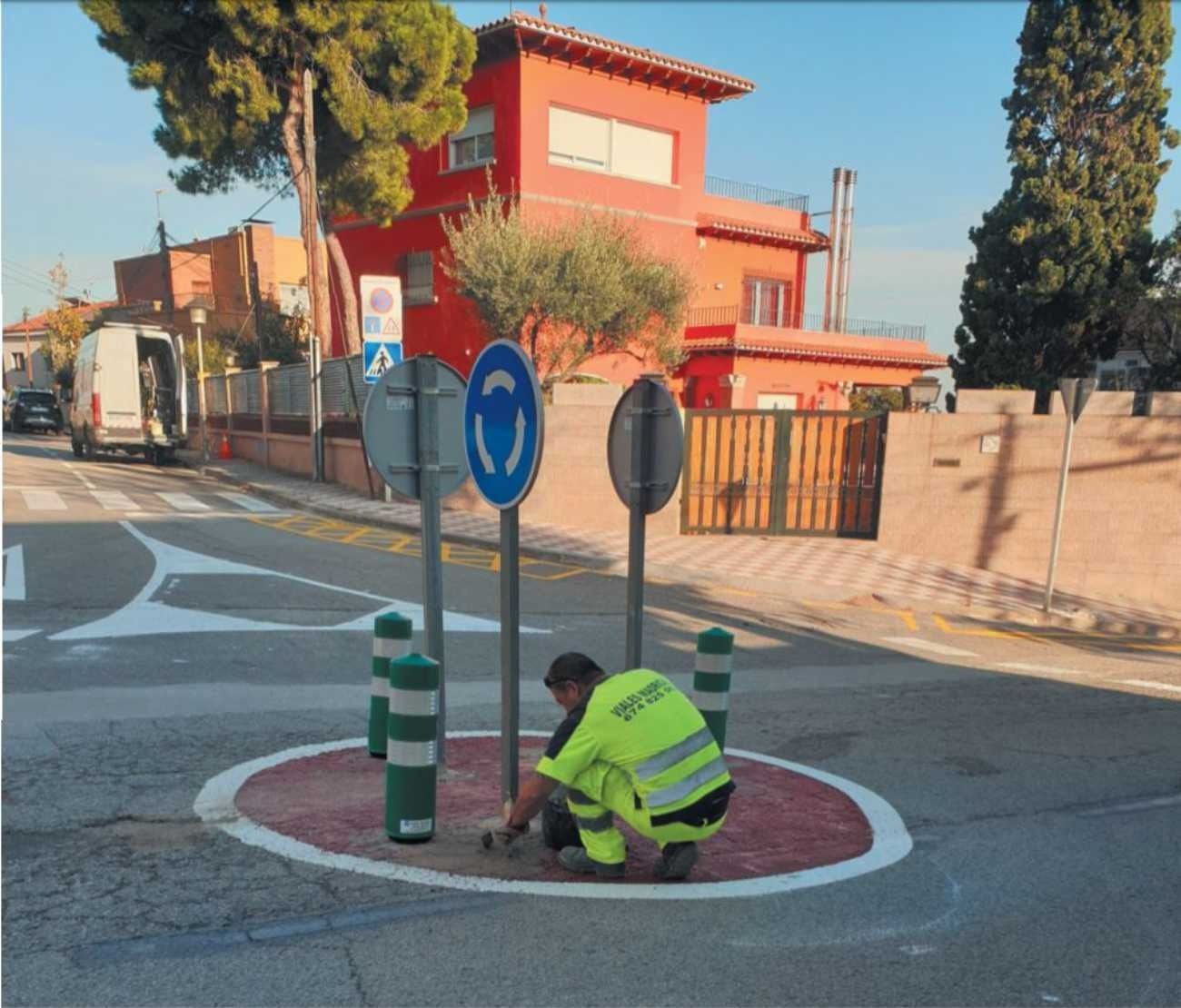 Un hombre con un chaleco amarillo está trabajando en una rotonda.