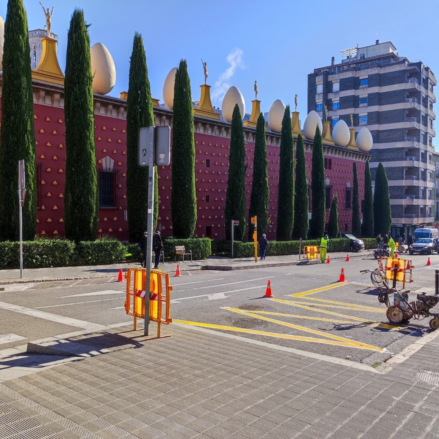 Un edificio rojo con muchos árboles delante.
