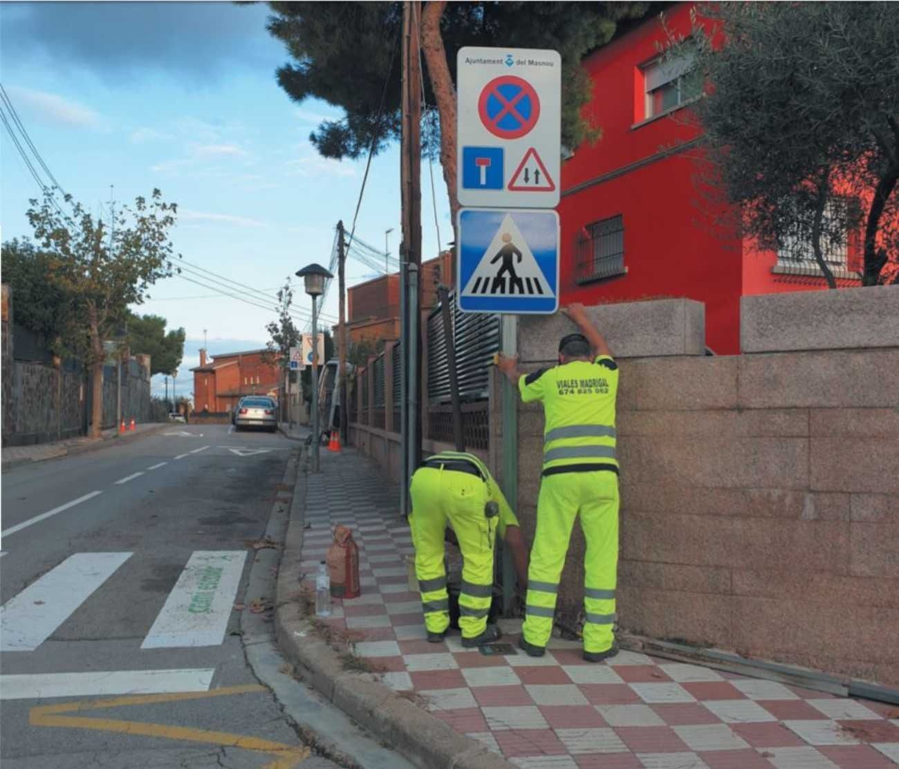 Dos hombres con pantalones amarillos están trabajando en una calle.