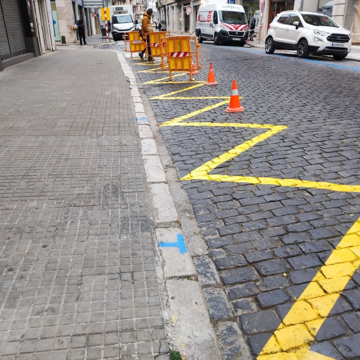 Una calle adoquinada con una T azul pintada en la acera