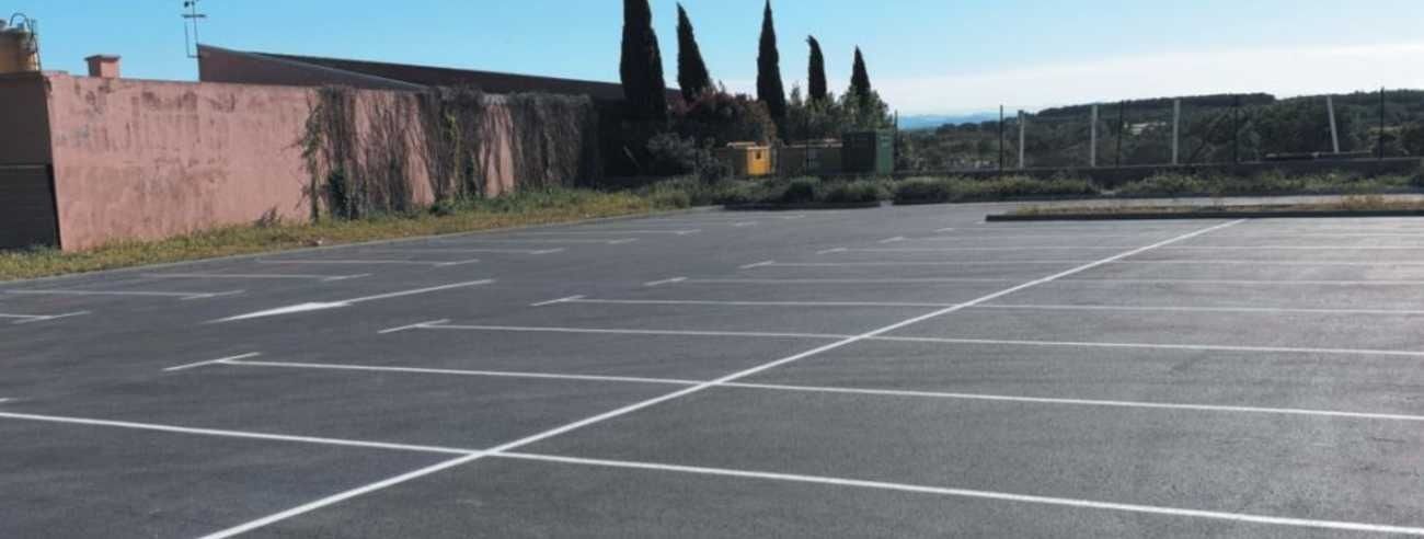 Un estacionamiento vacío con un edificio al fondo.