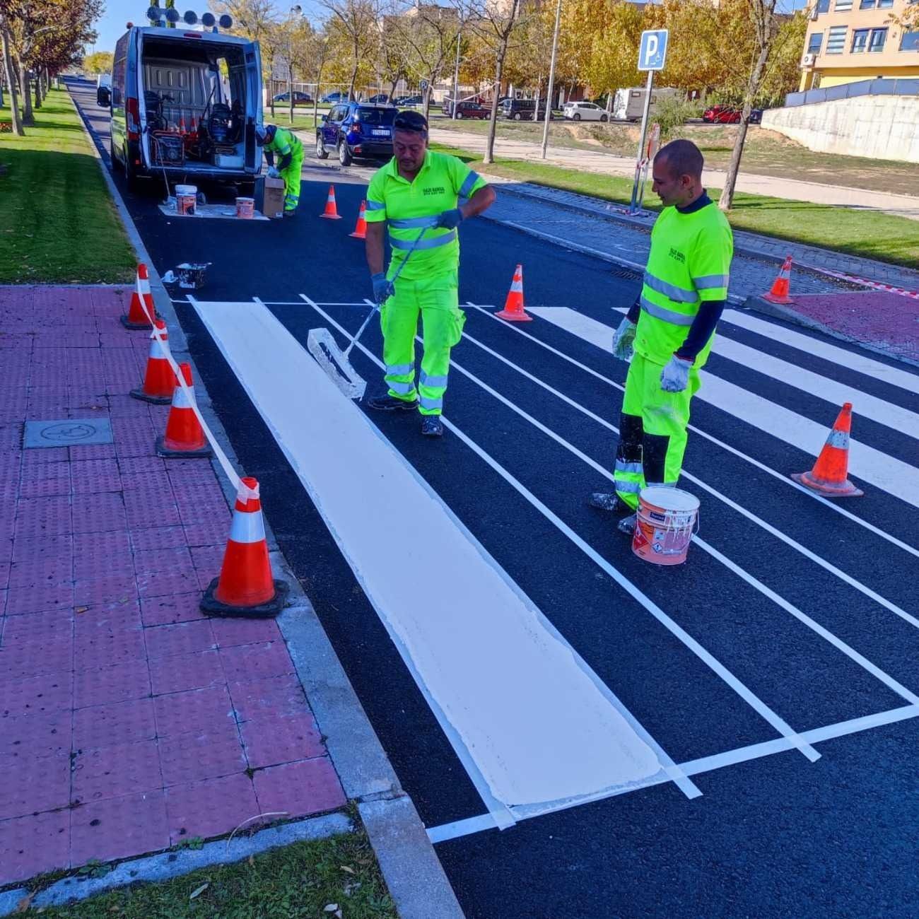 Dos hombres están pintando un paso de peatones en una calle.
