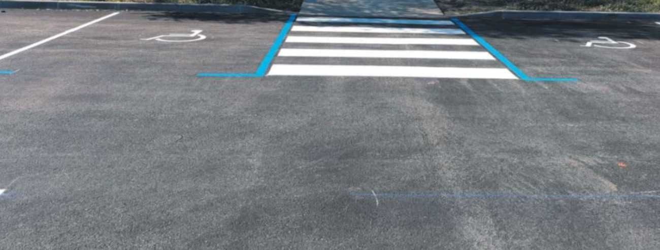 Un estacionamiento con un lugar para discapacitados y un paso de peatones.