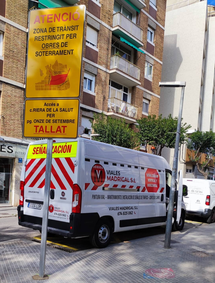 Una camioneta blanca está estacionada al lado de un cartel que dice tallat