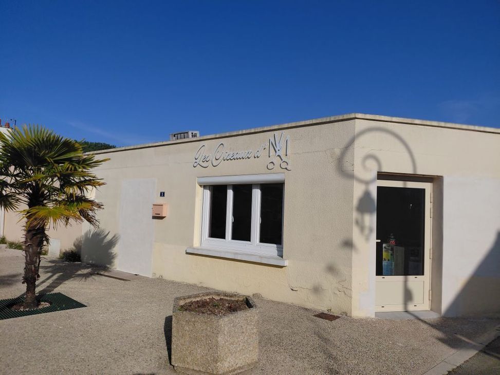 Petit bâtiment en stuc blanc avec un palmier, une fenêtre et une porte sous un ciel bleu clair