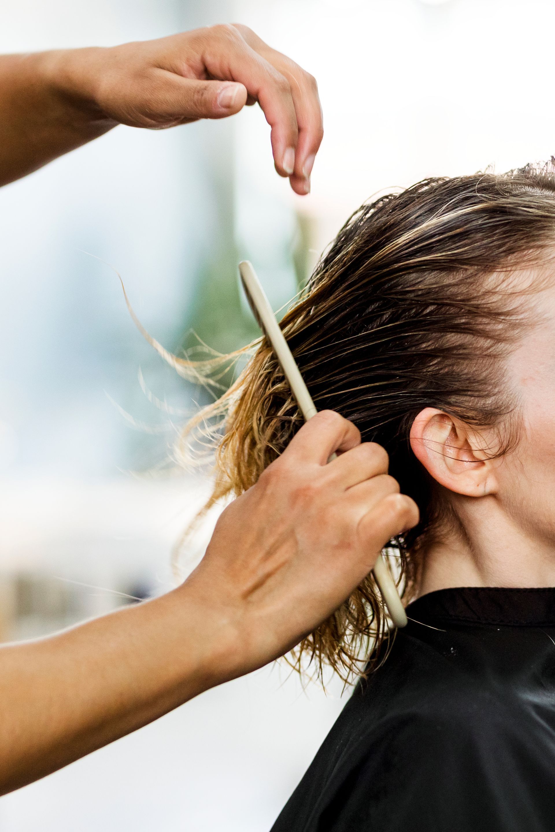 Coiffeuse peignant et coupant les cheveux courts d'une cliente au salon