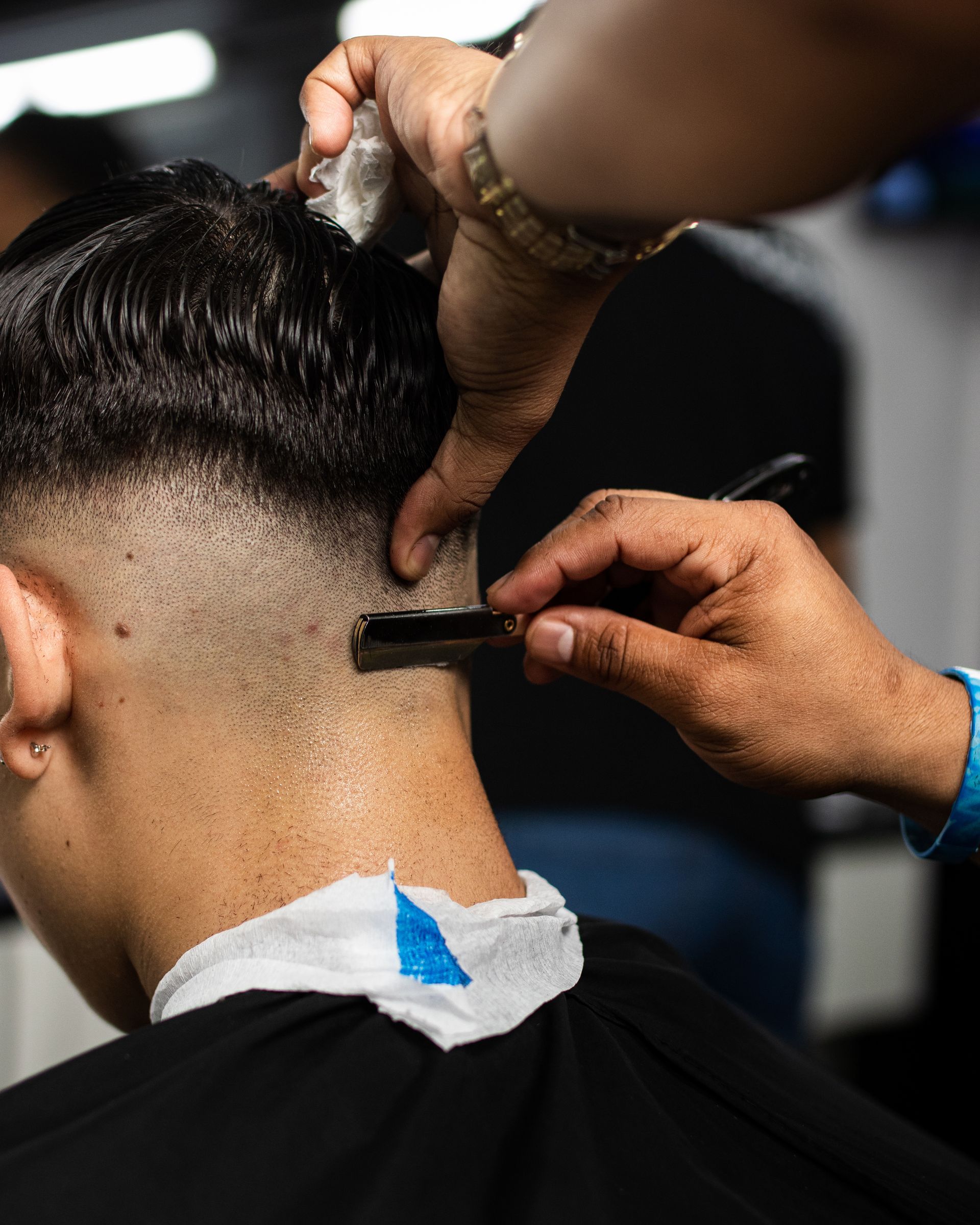 Un coiffeur rase la nuque d'un client avec une tondeuse électrique dans un salon de coiffure.